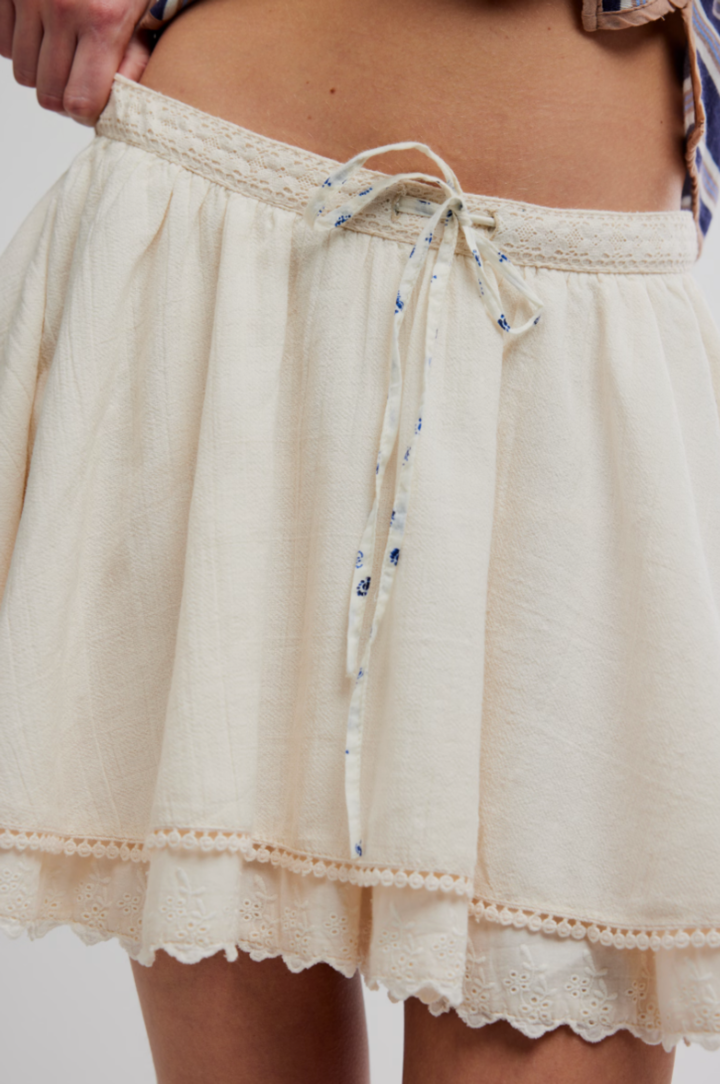 Mini skirt in tea color with lace trim and waist tie, shown worn; suitable for casual or semi-casual occasions.