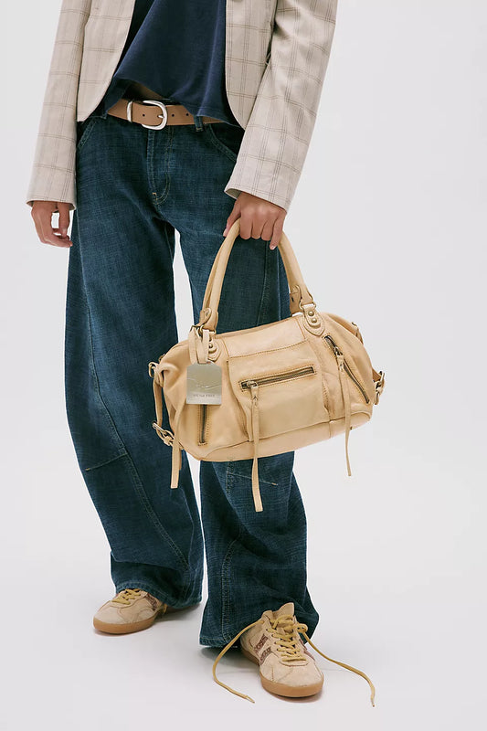 Butter yellow leather shoulder bag carried by person in wide-leg jeans, checked blazer, and tan sneakers.