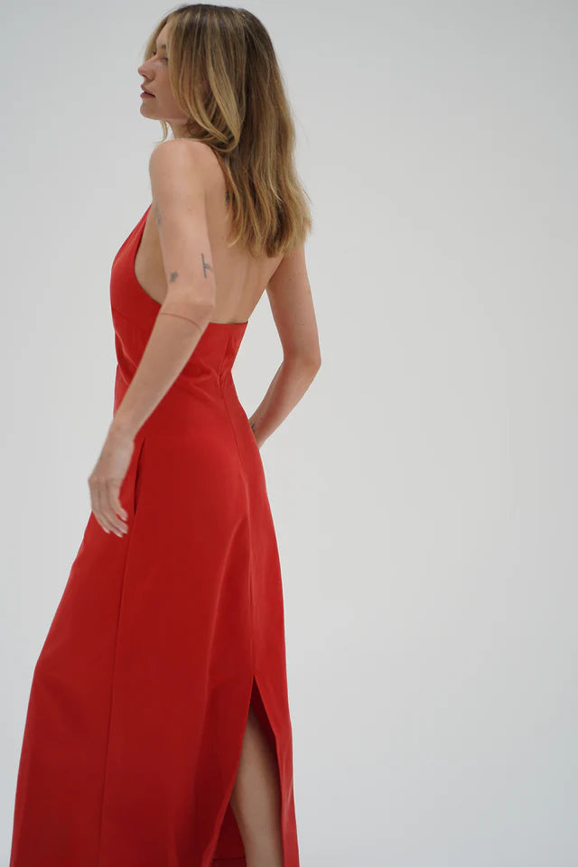 Side view of person wearing a red chambray halter dress, shown against a plain light background.