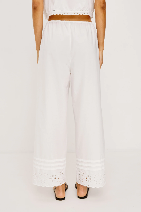 Back view of white cotton poplin straight-leg pants with eyelet hem, worn with heels.