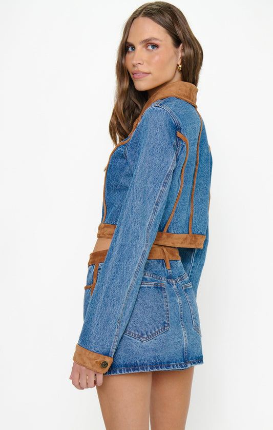 Side view of a woman in an indigo faux fur jacket and matching mini skirt set.