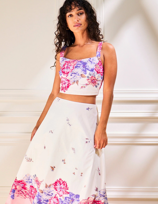 Woman wears a Camellia print organic cotton top and a white skirt, suitable for casual or daytime wear.