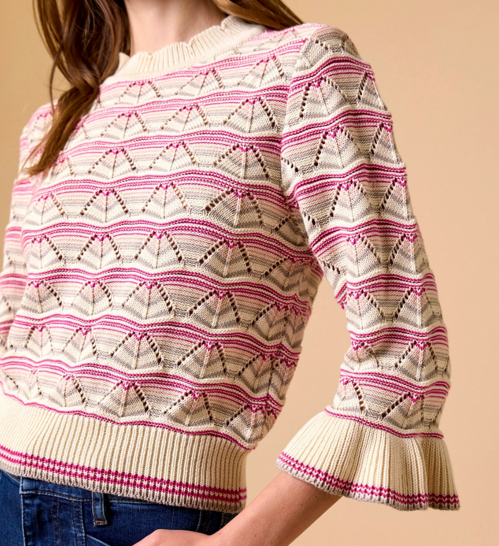 Ivory knit sweater with pink and maroon patterns, styled for casual wear, shown on woman against a beige background.