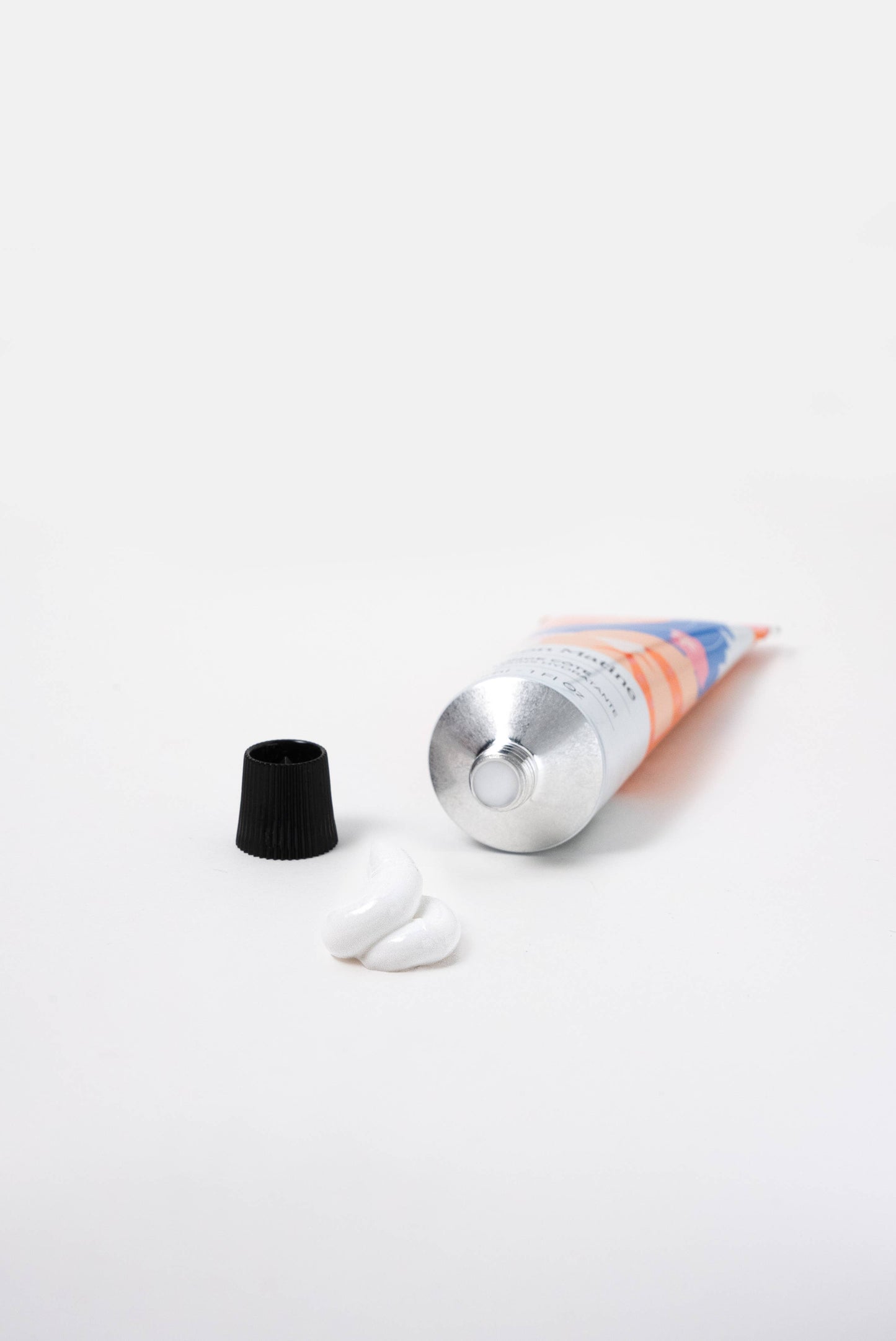Silver metal tube of hand cream, 30ml, with white cream dispensed onto a plain white surface.