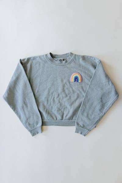 Cropped eucalyptus-green sweatshirt with long sleeves and a small chenille rainbow patch; ideal for casual wear.