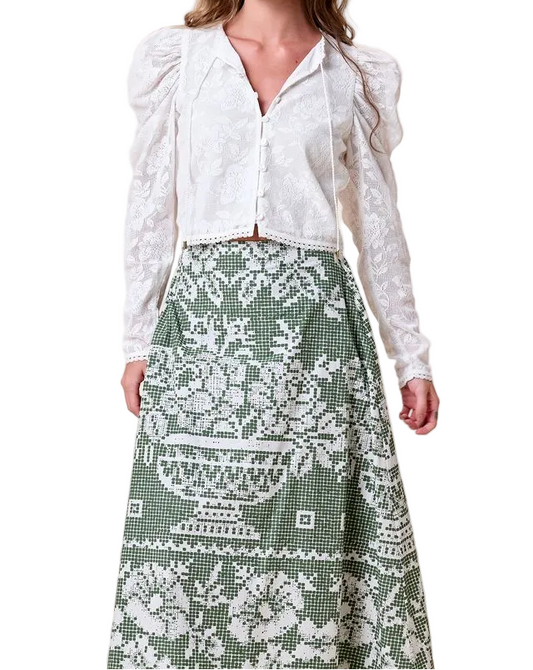 White blouse paired with a green skirt featuring a white floral and vase print, suitable for casual or semi-formal wear.