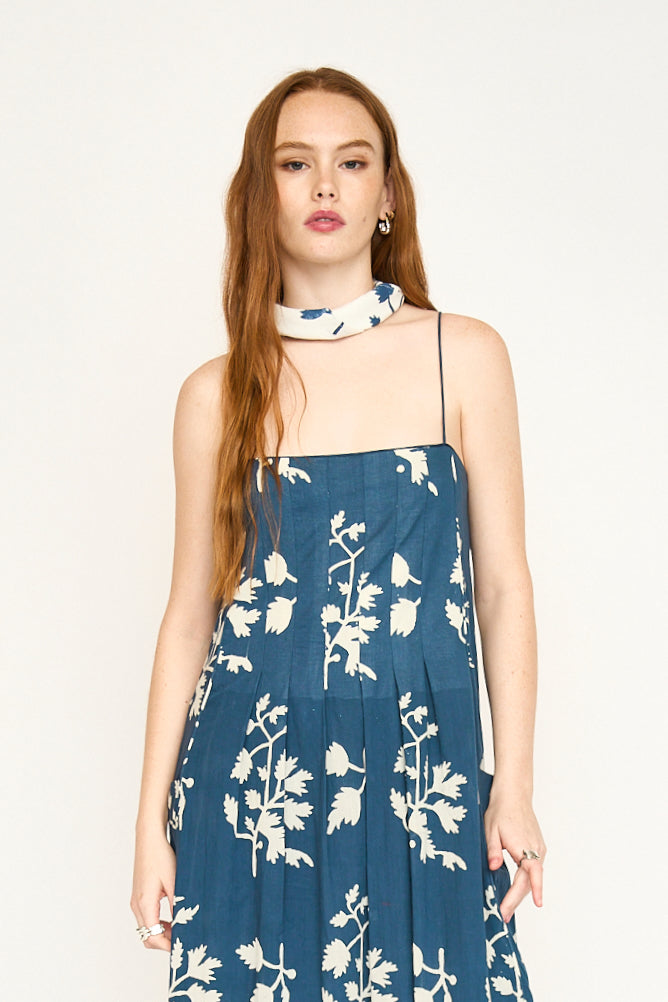 Woman wearing a blue hand block printed dress and Summer Fig bandana, standing against a plain background.