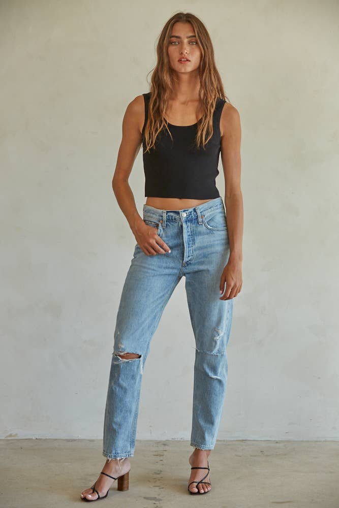 Sleeveless beige knit tank, paired with ripped light blue jeans and heeled sandals, shown against a plain background.
