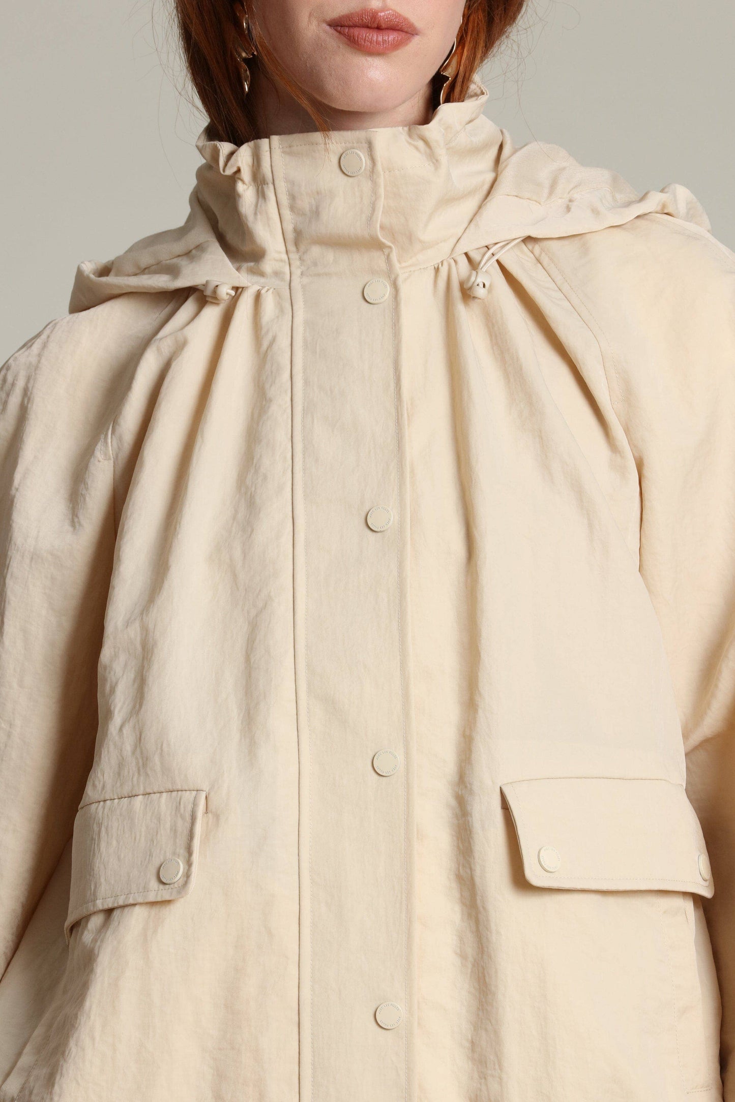 Cream balloon-sleeve windbreaker with large pockets and high collar, shown from shoulders to mid-torso.
