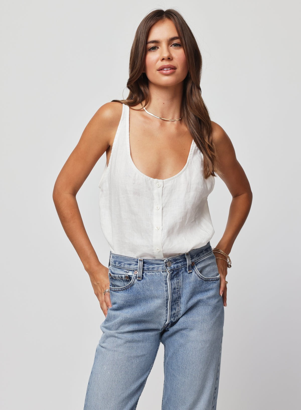 Woman wearing a white sleeveless top and blue jeans