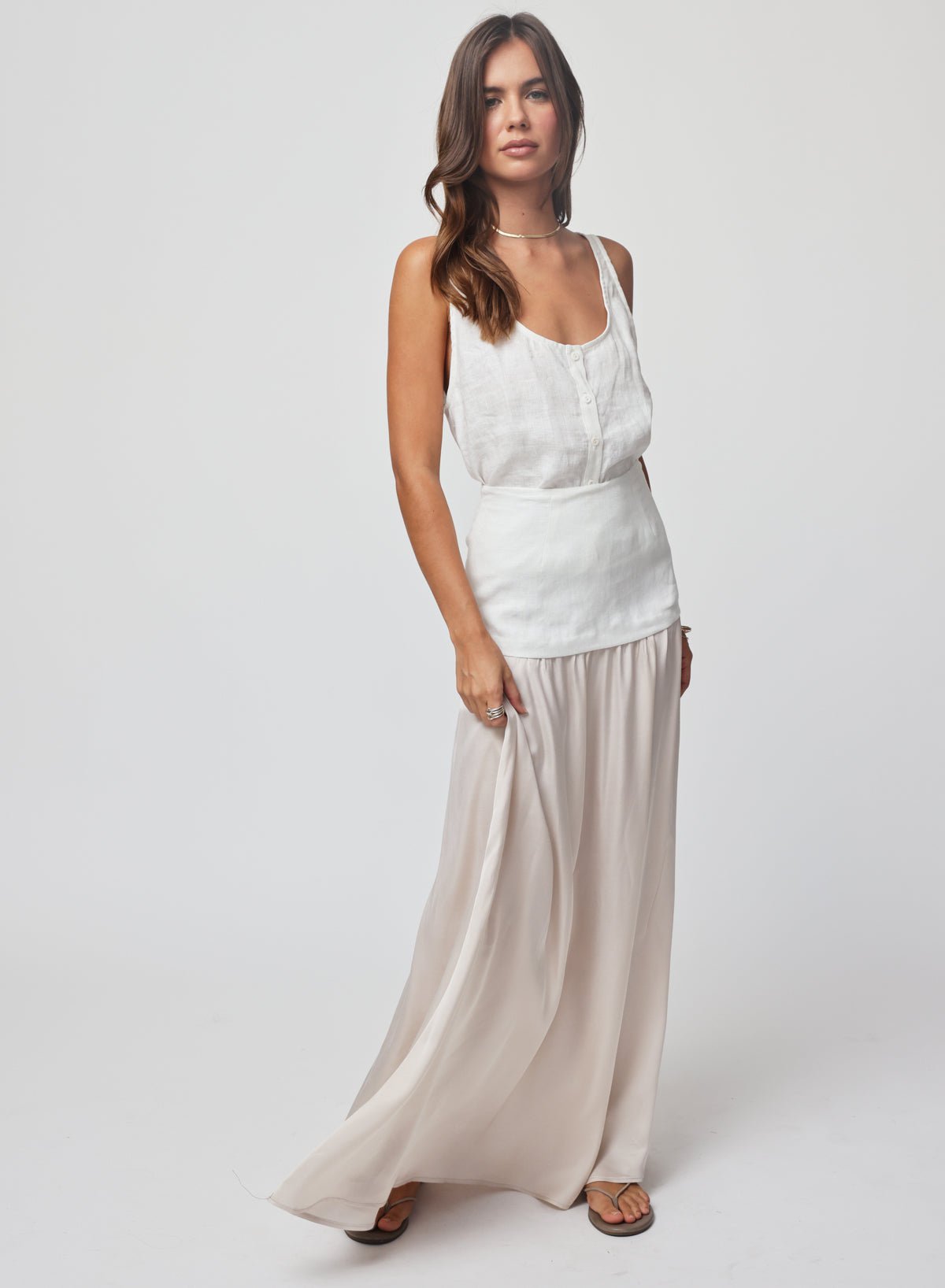 Woman wearing a white sleeveless top and beige skirt