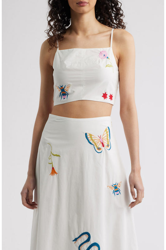 Woman in a white top with colorful designs 