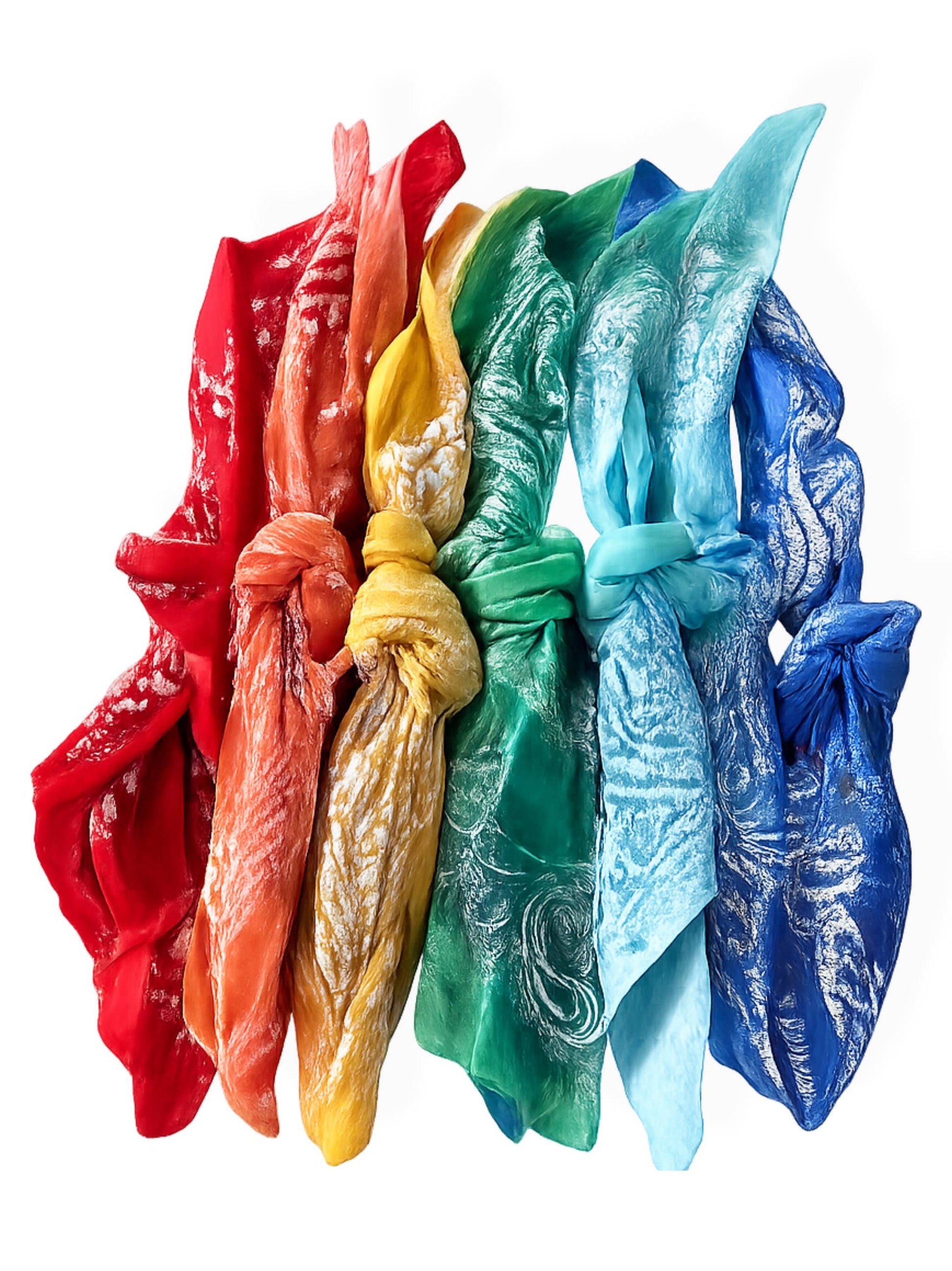 Six pale cotton bandanas, knotted and laid in a row, evoke a relaxed beach vibe.