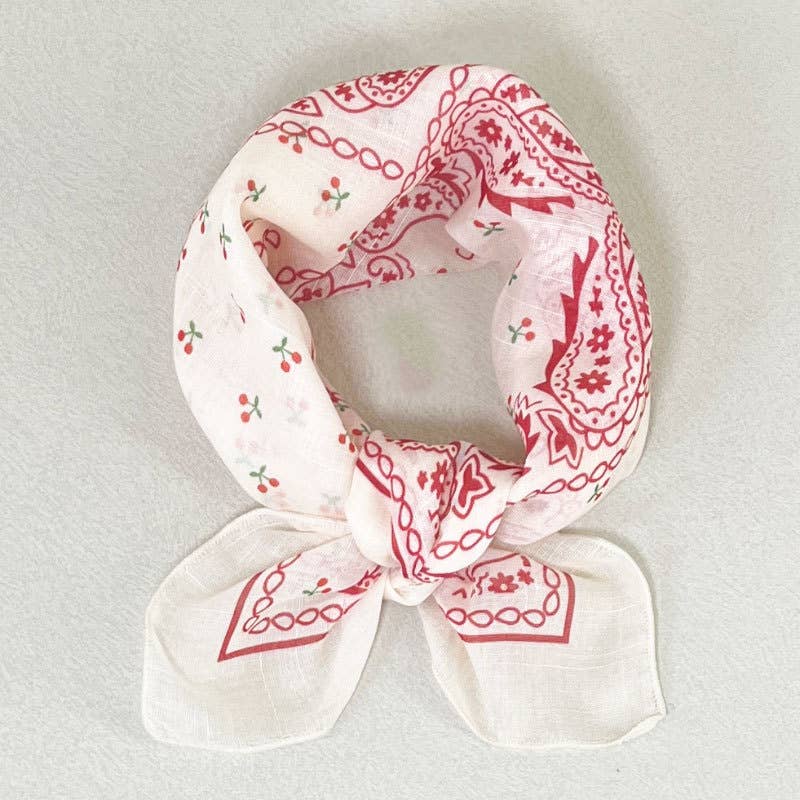 Red cotton bandana with paisley and cherry patterns, suitable as a playful accessory for everyday wear.