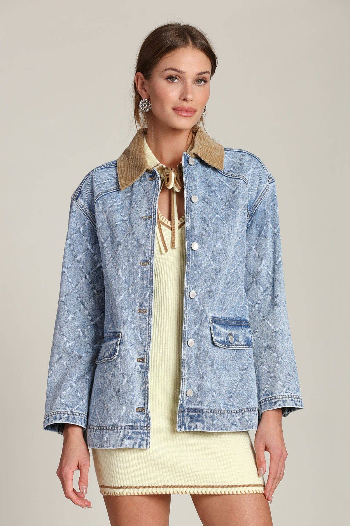 Model wears a blue denim barn jacket over a cream mini dress, photographed against a plain backdrop.