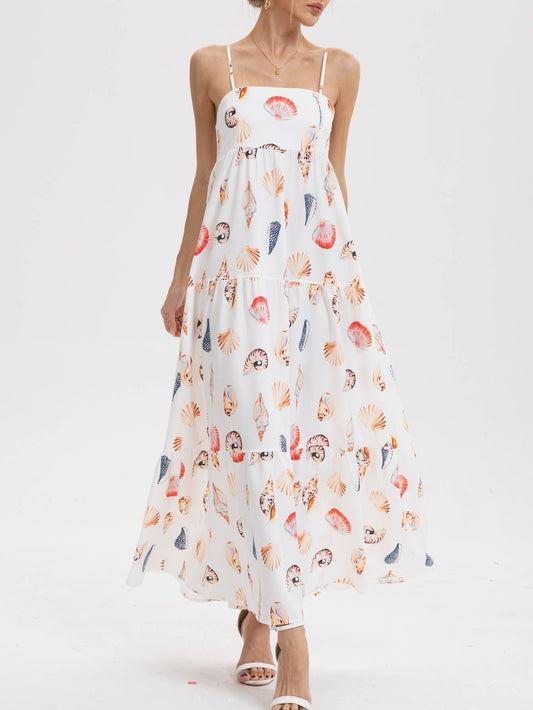 White maxi dress with colorful seashell prints, spaghetti straps, lightweight fabric, paired with white heels.