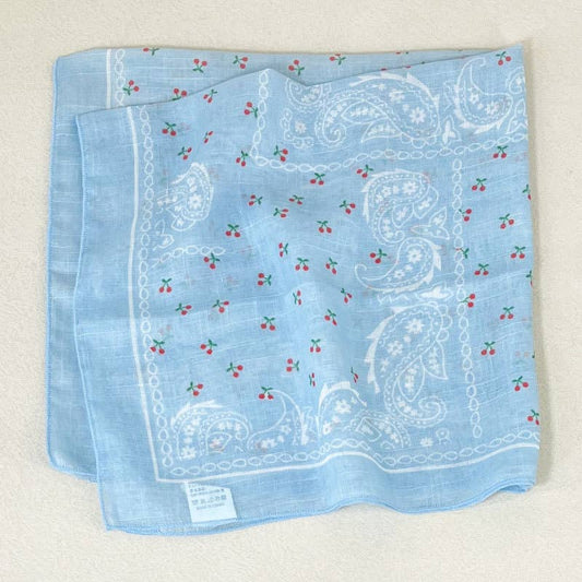 Light blue bandana with a paisley pattern and small red cherries, made from soft fabric for versatile wear.