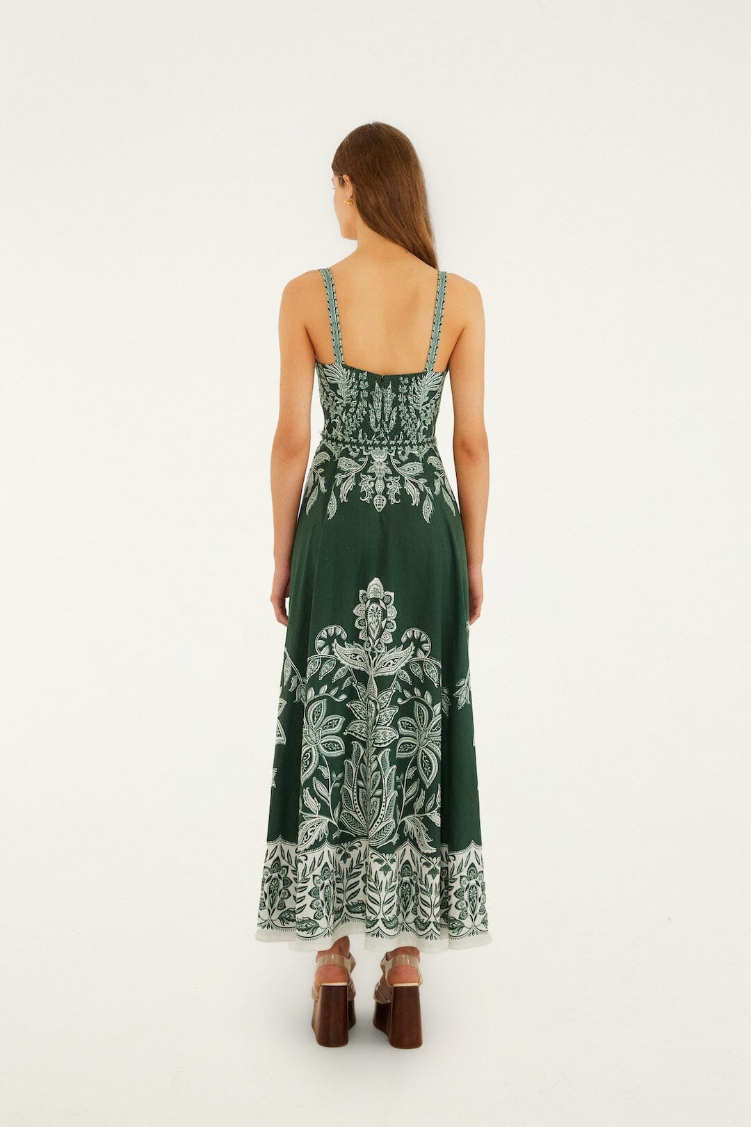 Back view of a woman in a dark green maxi dress with belt buckles, suitable for casual or semi-formal occasions.