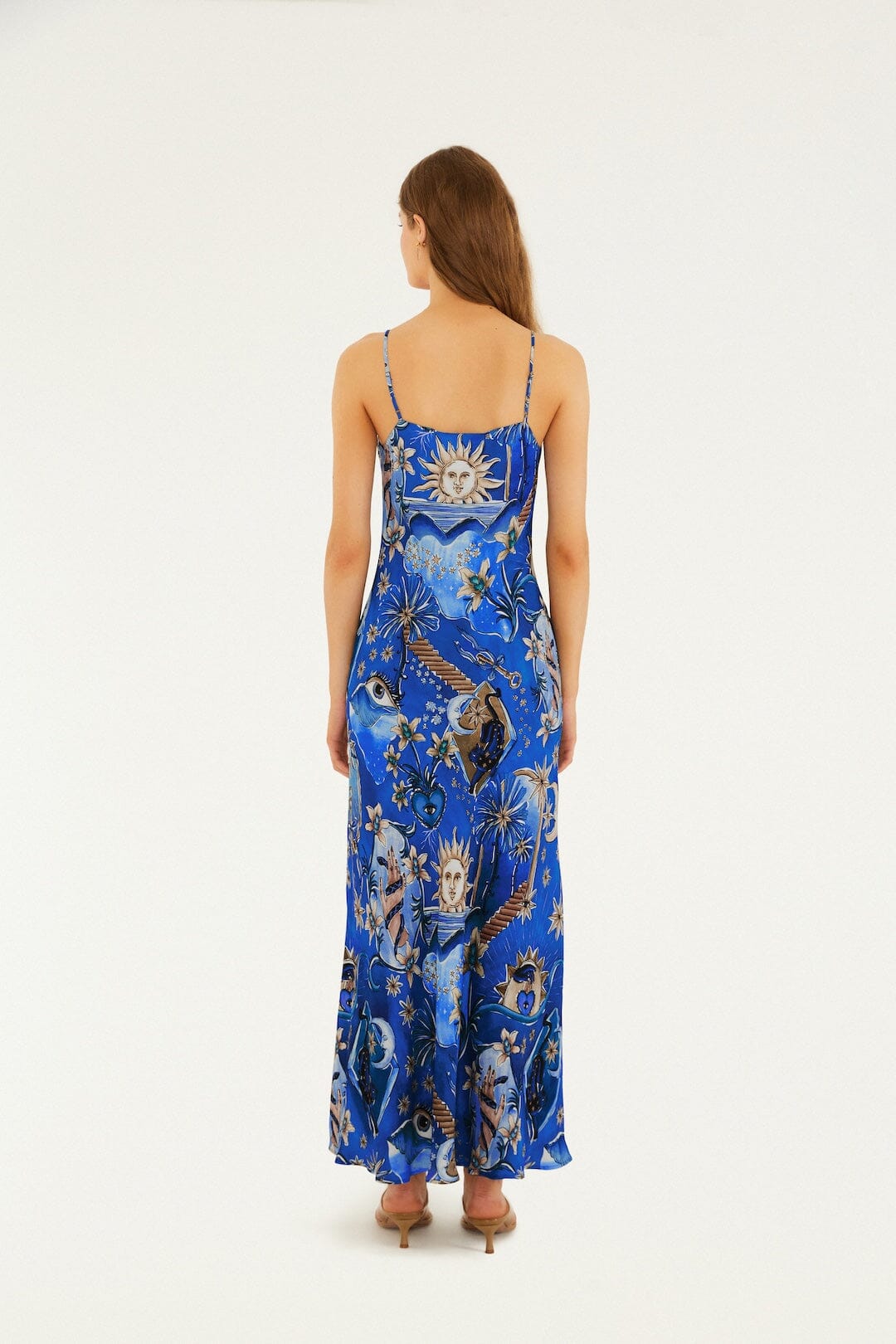 Woman wears a blue maxi dress with celestial patterns, viewed from the back. Suitable for casual or evening occasions.