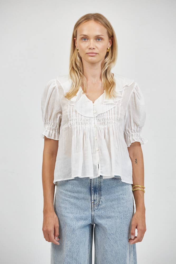 Woman in off-white Sasha Top and light blue jeans against a white background; casual outfit highlights tops fabric and fit.