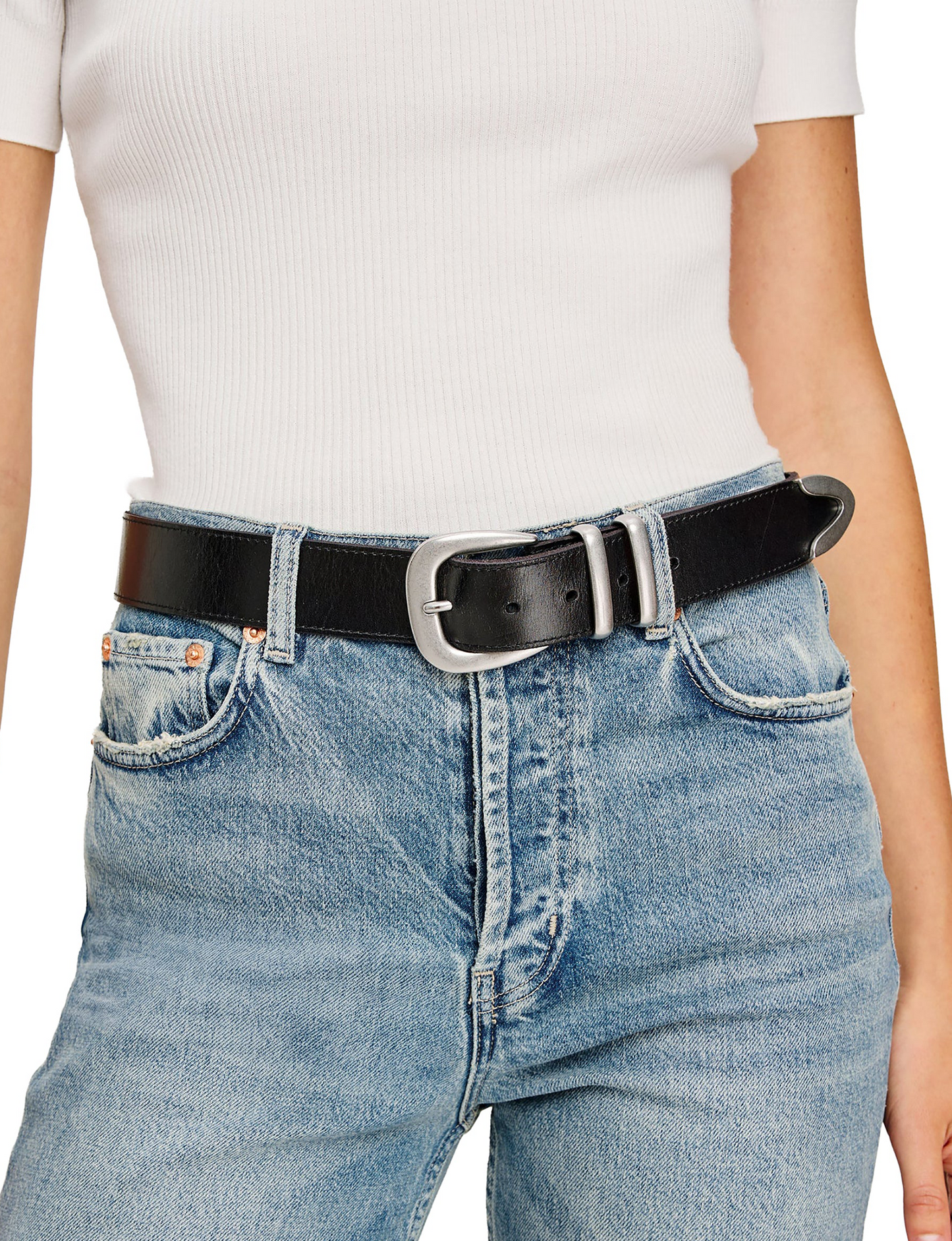 Black leather belt with silver hardware worn over blue jeans and a white ribbed top.