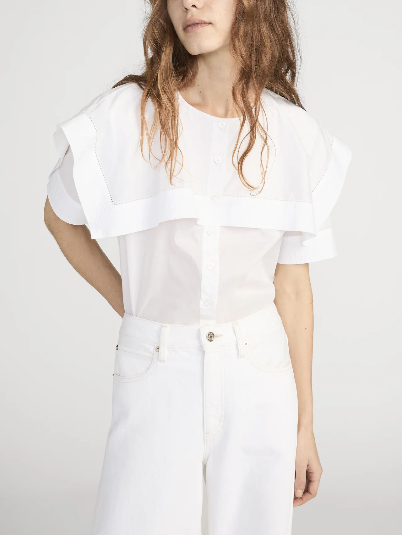 Woman wearing a white silk cape shirt with large collar and high-waisted white pants. Suitable for formal or work settings.