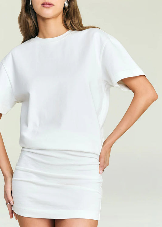 Woman in ivory Seroya Georgie dress, one hand on hip, stands against a light background.