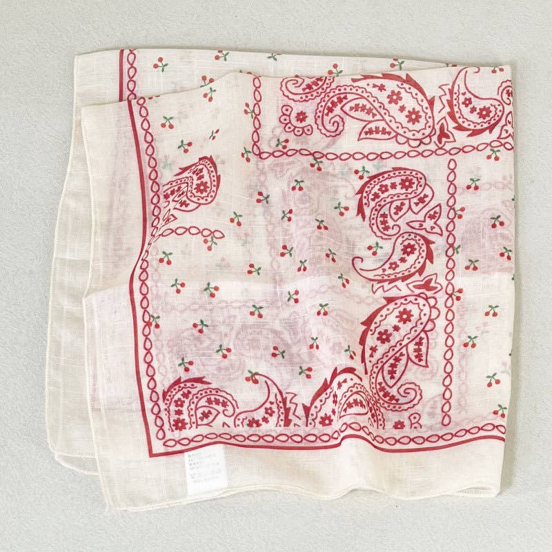 Beige cotton bandana with cherry, floral, and paisley patterns; suitable for casual or accessory use.