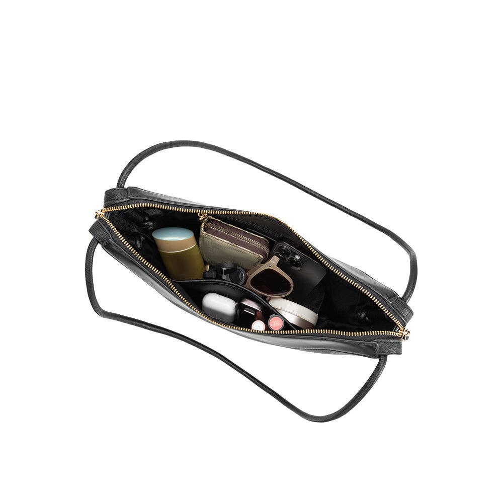 Black recycled vegan shoulder bag, seen open from above, containing sunglasses and cosmetics.