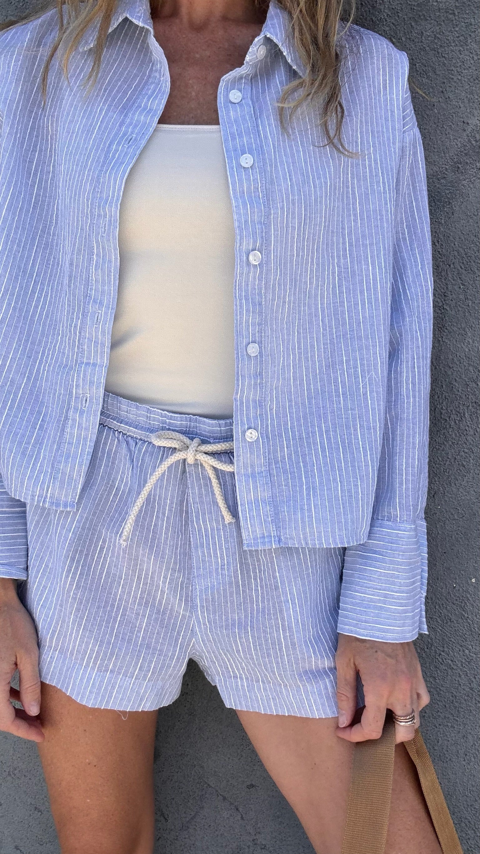 Light blue shorts paired with a striped button-up shirt layered over a white tank top, casual everyday outfit.