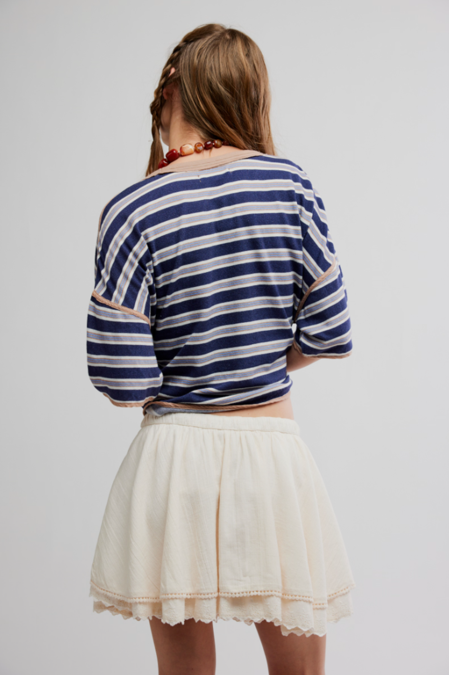 Person wearing a striped shirt and light-colored mini skirt, standing with back to camera; skirt appears soft and casual.