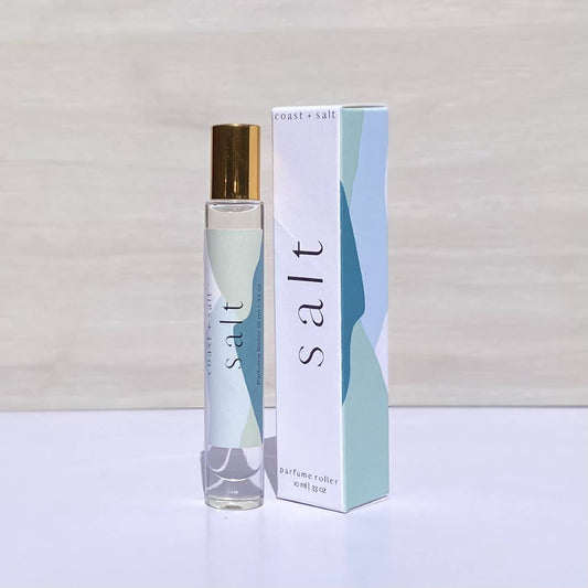 Salt perfume roller with driftwood notes beside a pastel-colored, abstract-patterned box.