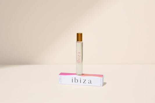 Gold-capped Ibiza perfume roller sits atop its box, designed for easy application of fruity floral fragrance.