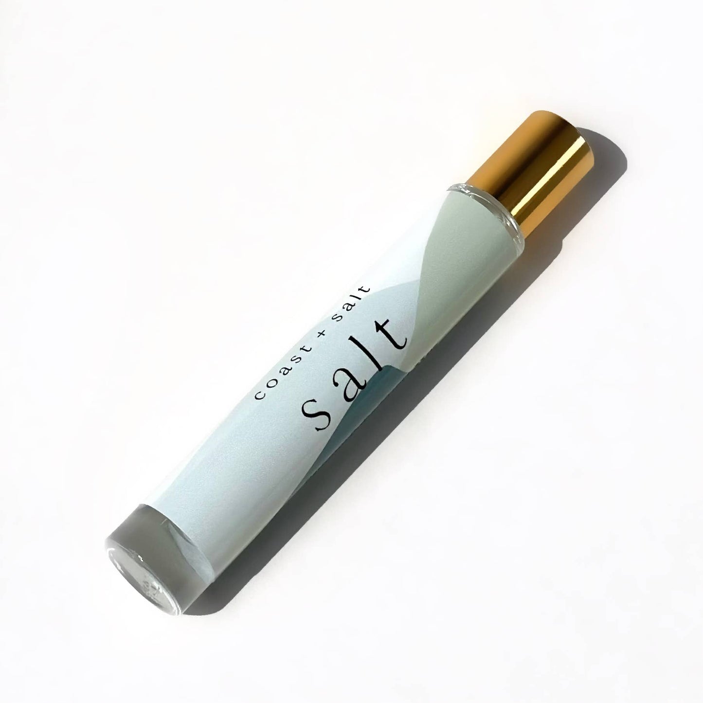 Glass perfume roller with gold cap, containing fragrance notes of driftwood and sea salt.