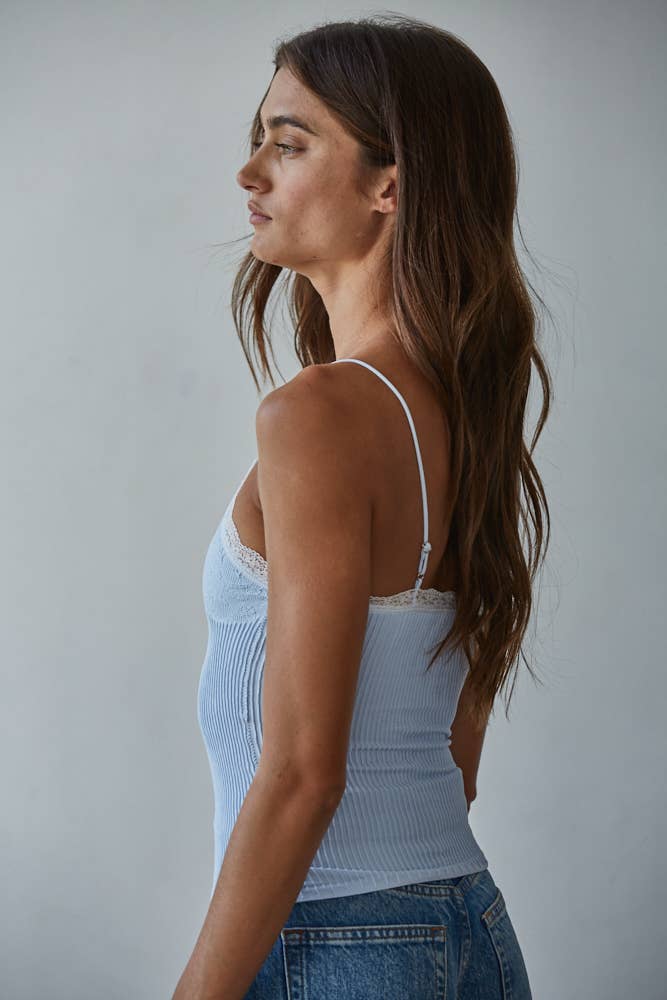 Woman with long brown hair wears a beige knit Ava Top and blue jeans in profile against a neutral background.