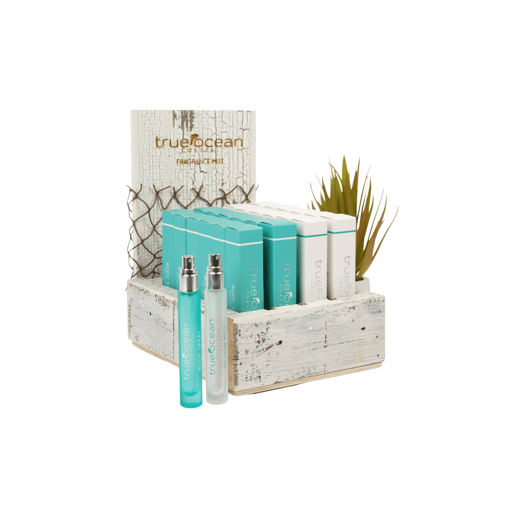 Turquoise and white ocean body spray bottles in a wooden box with plant and rustic netting decor.