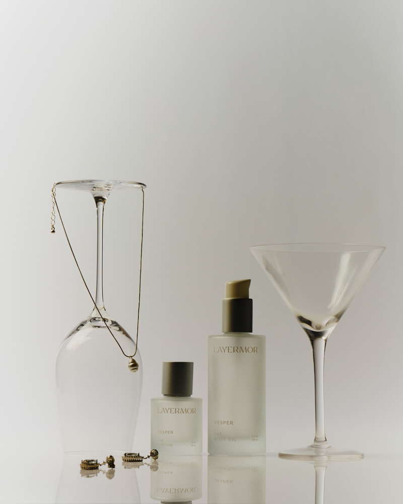 Clear glass bottle of body oil with vegan ingredients on a white background, highlighting its use for skin care.