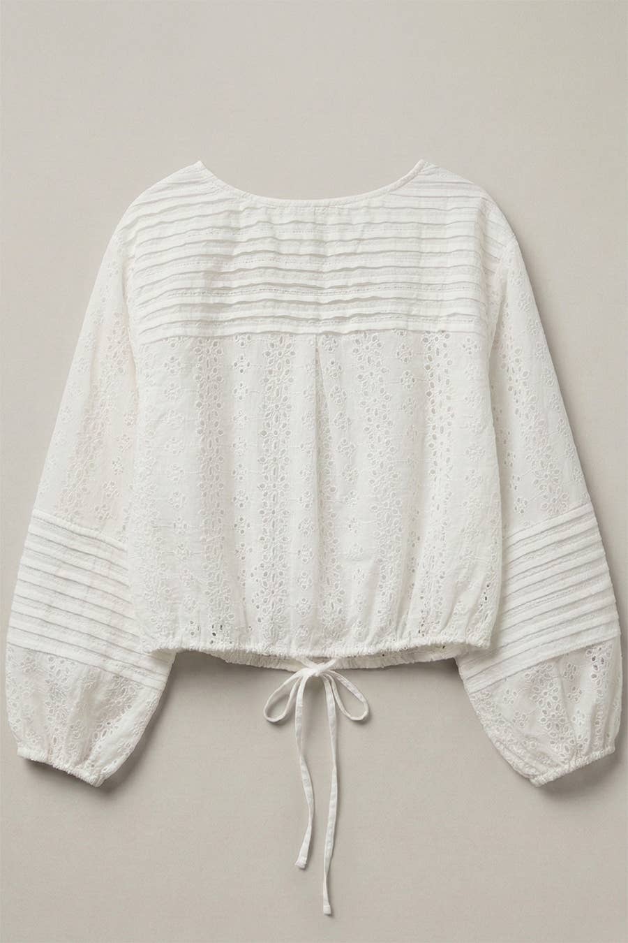 Off-white long-sleeve top with eyelet button front, pleats, round neck, and drawstring waist.