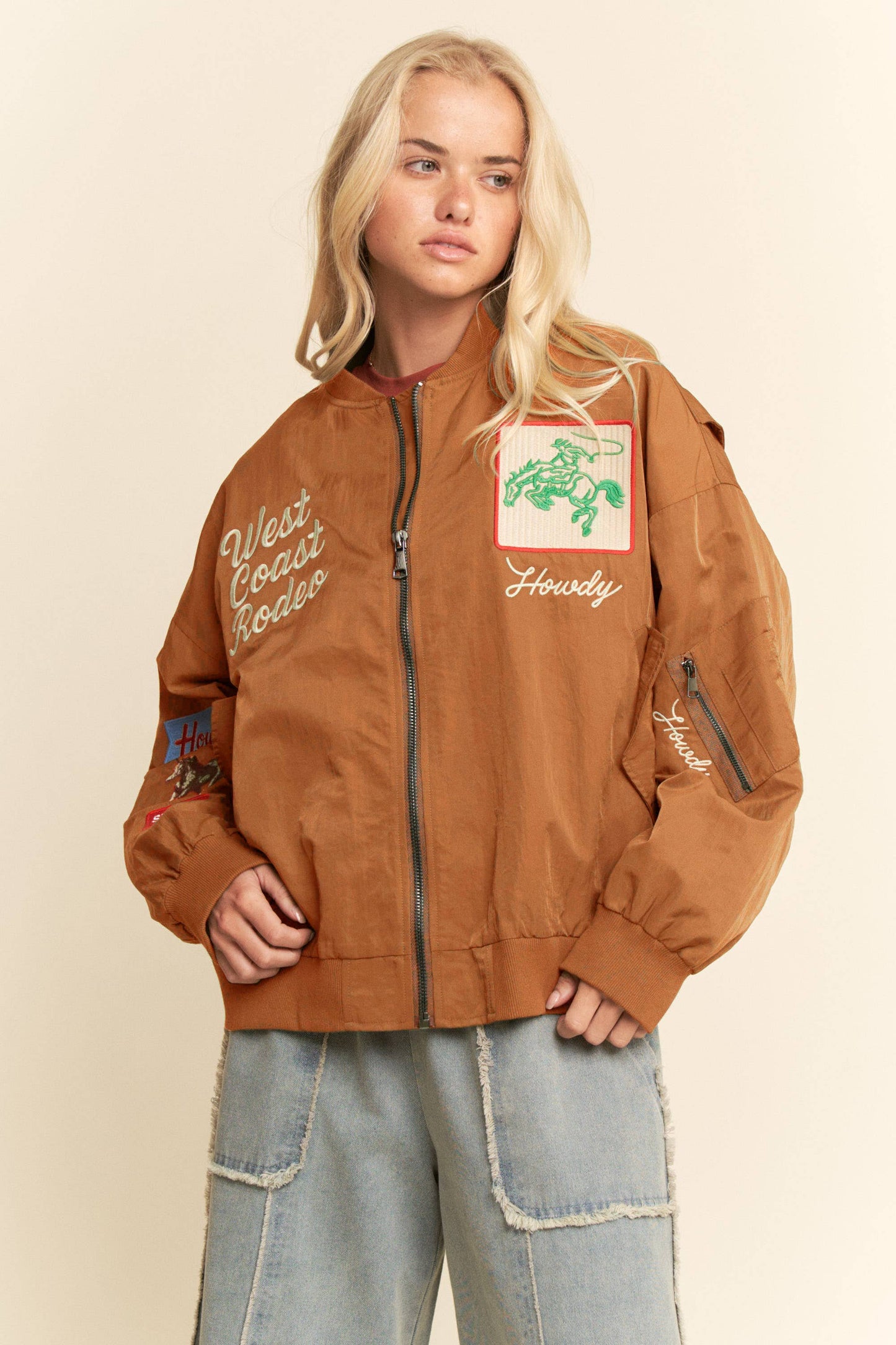 Woman wearing an embroidered bomber jacket, featuring western details, suitable for festivals.