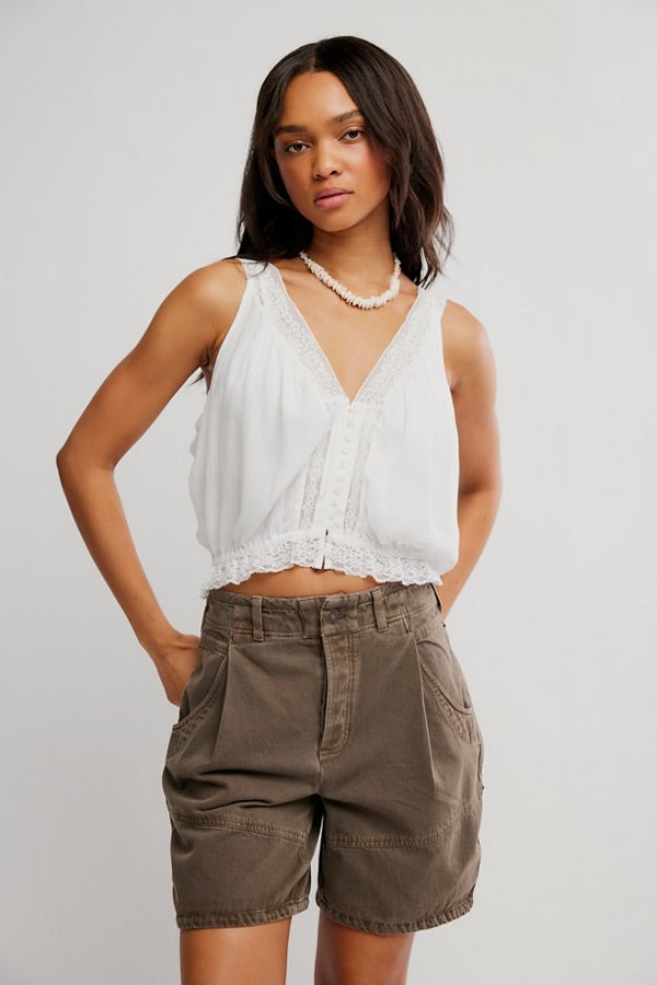 Woman wears ivory tank top and brown high-waisted shorts, both lightweight, shown against a plain background.