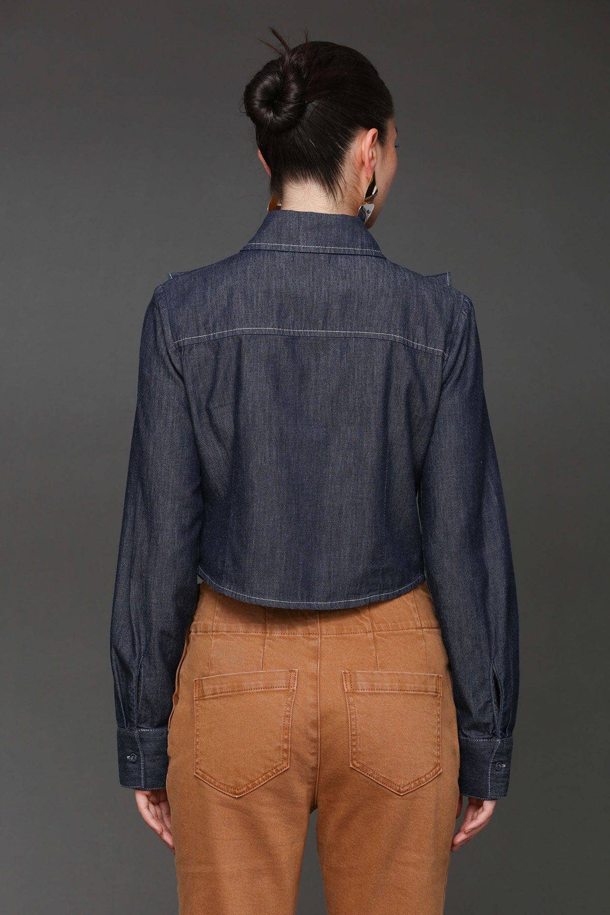 Back view of woman in a cropped denim shirt and high-waisted brown boho pants, highlighting fabric and fit.