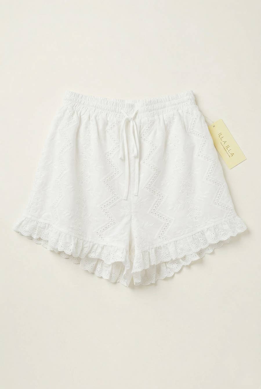 Off-white ruffle shorts with elastic waist, scalloped hem, and yellow side tag; suitable for casual wear.