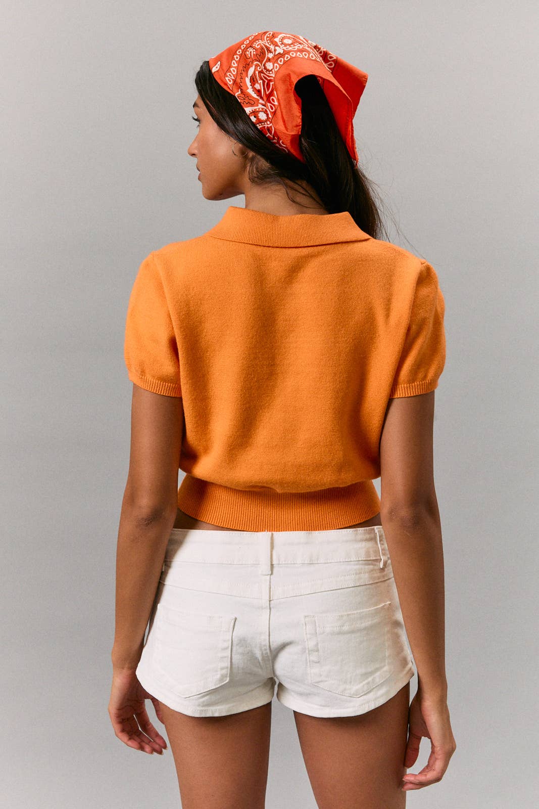 Tangerine knit sweater top in size small, styled with white shorts and a red bandana against gray background.