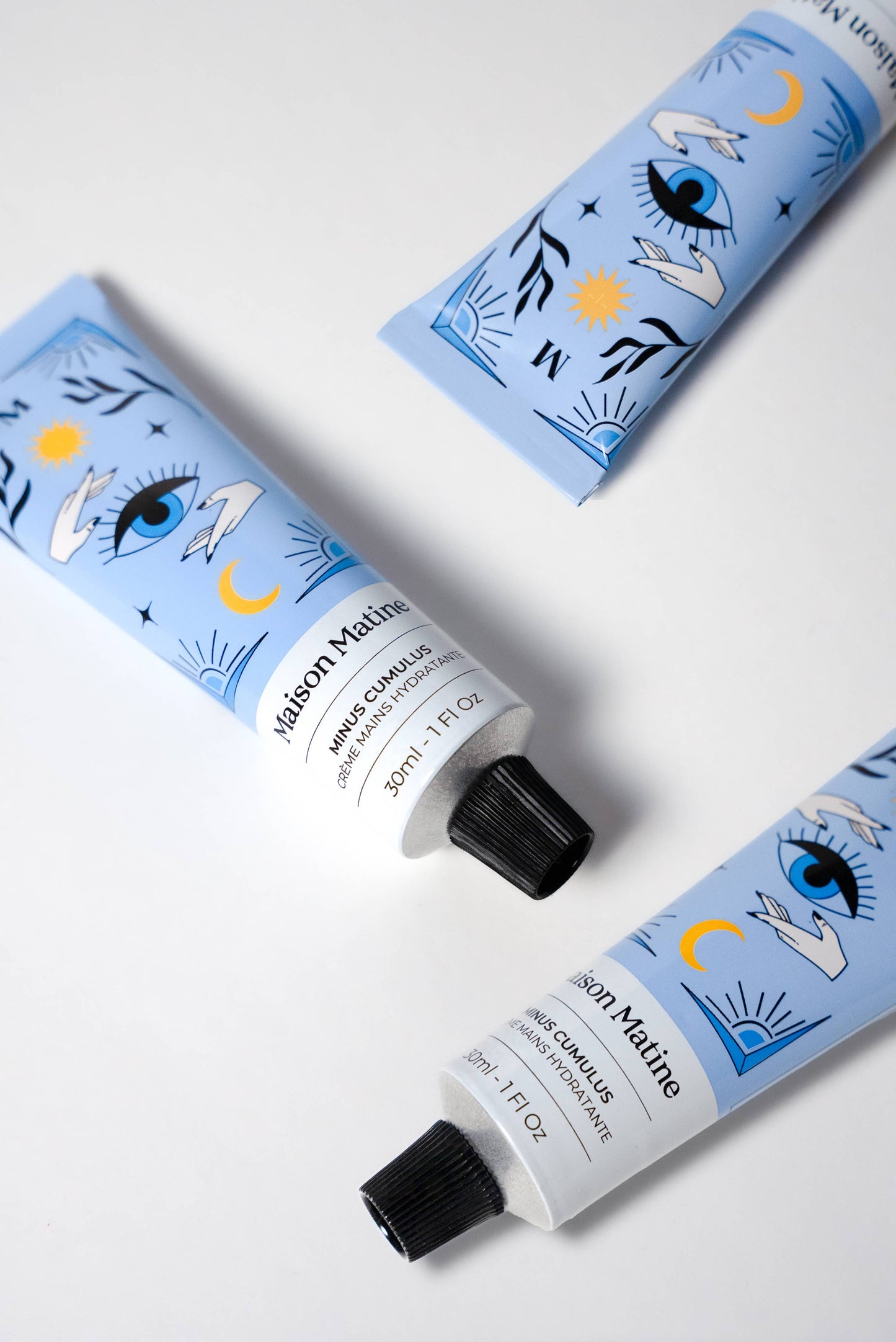 Three blue Maison Matine Minus Cumulus Hand Cream tubes, 30ml each, feature eye, star, and moon graphics on the packaging.