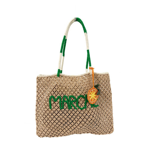 Beige tote bag with green logo, green-and-white handles, orange citrus charm; canvas material for everyday use.
