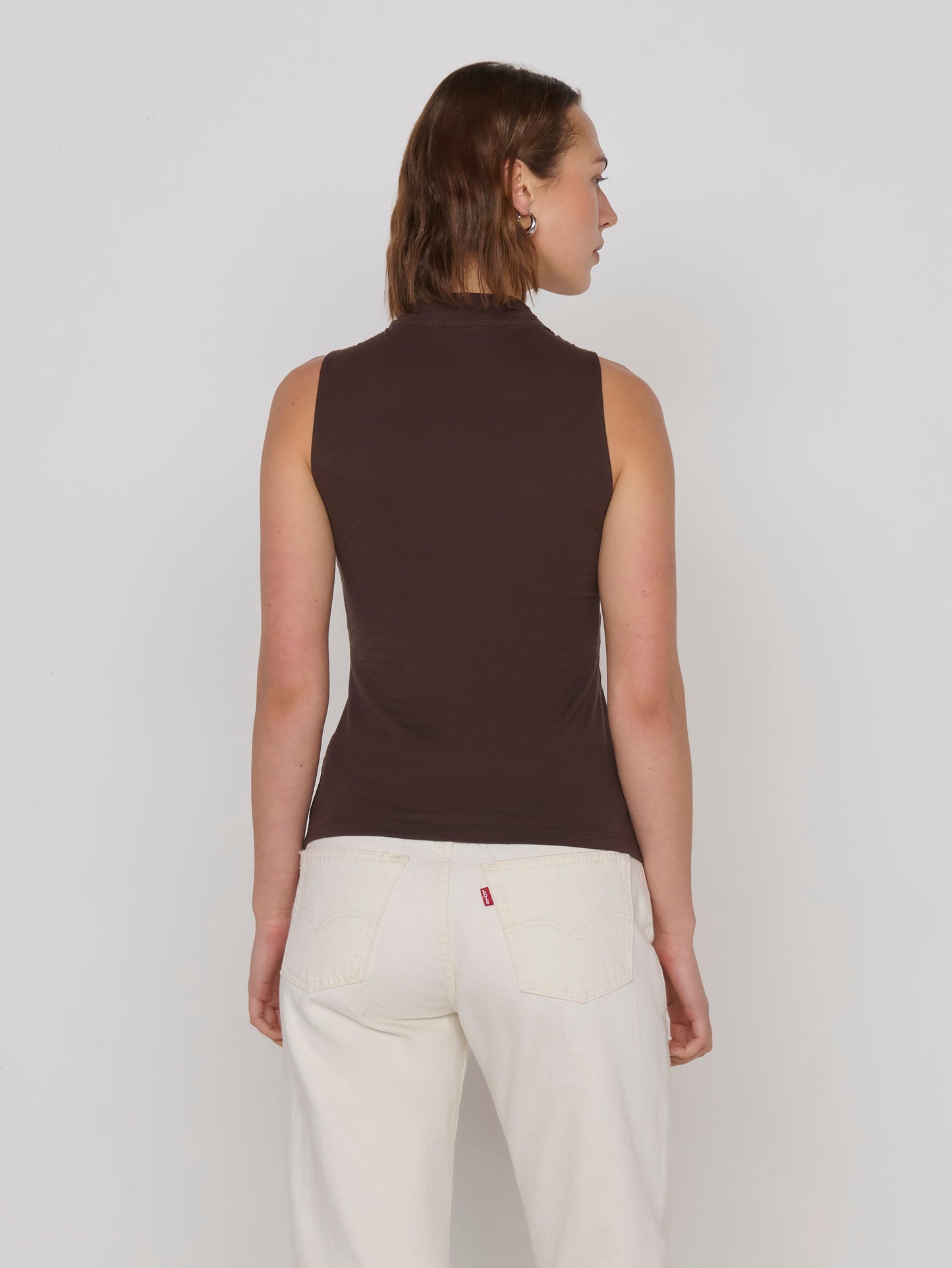 A woman wearing a dark brown halter-style top with a twisted crossover neckline