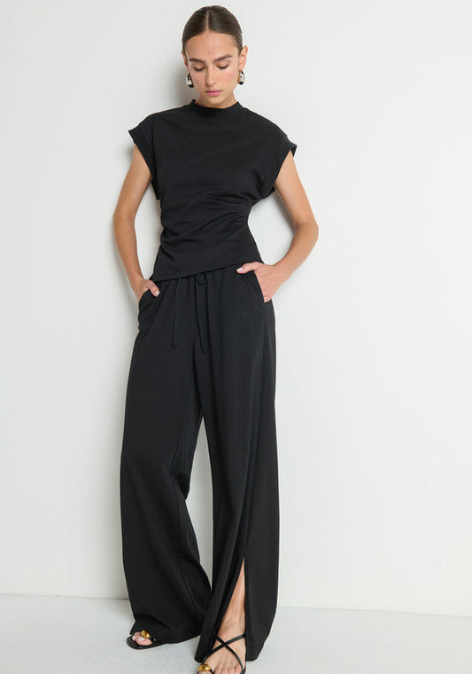 Black shirred side top and wide-leg black pants with front slits, shown against a white background.