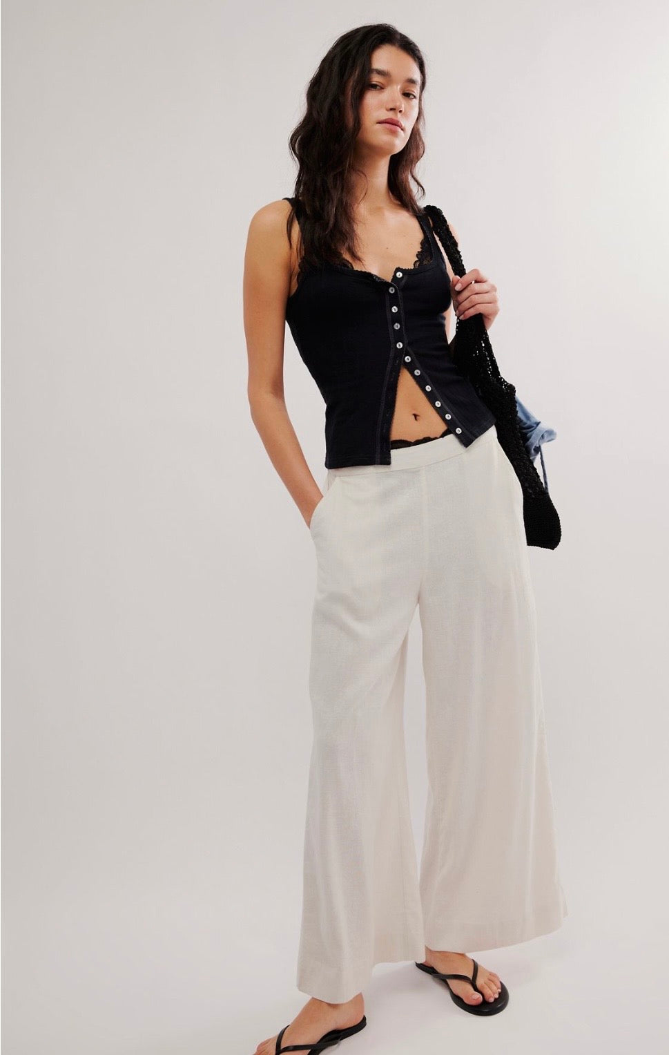 Black pointelle tank top, white wide-leg pants, black sandals, and a shoulder bag. Casual outfit suitable for warm weather.