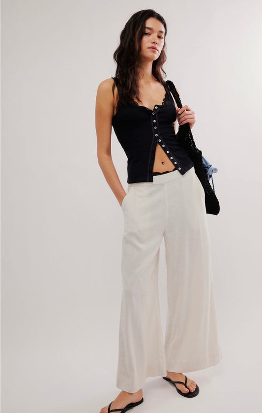 Black pointelle tank top, white wide-leg pants, black sandals, and a shoulder bag. Casual outfit suitable for warm weather.