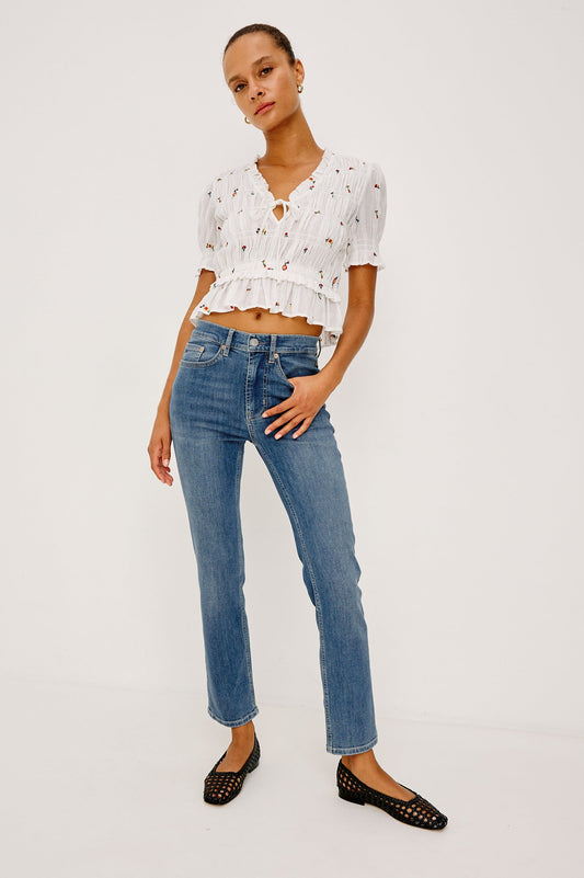 Woman wearing a white floral top and blue jeans 